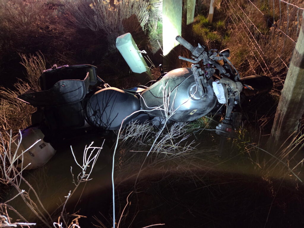 Crashed motorcycle on the side of the highway.