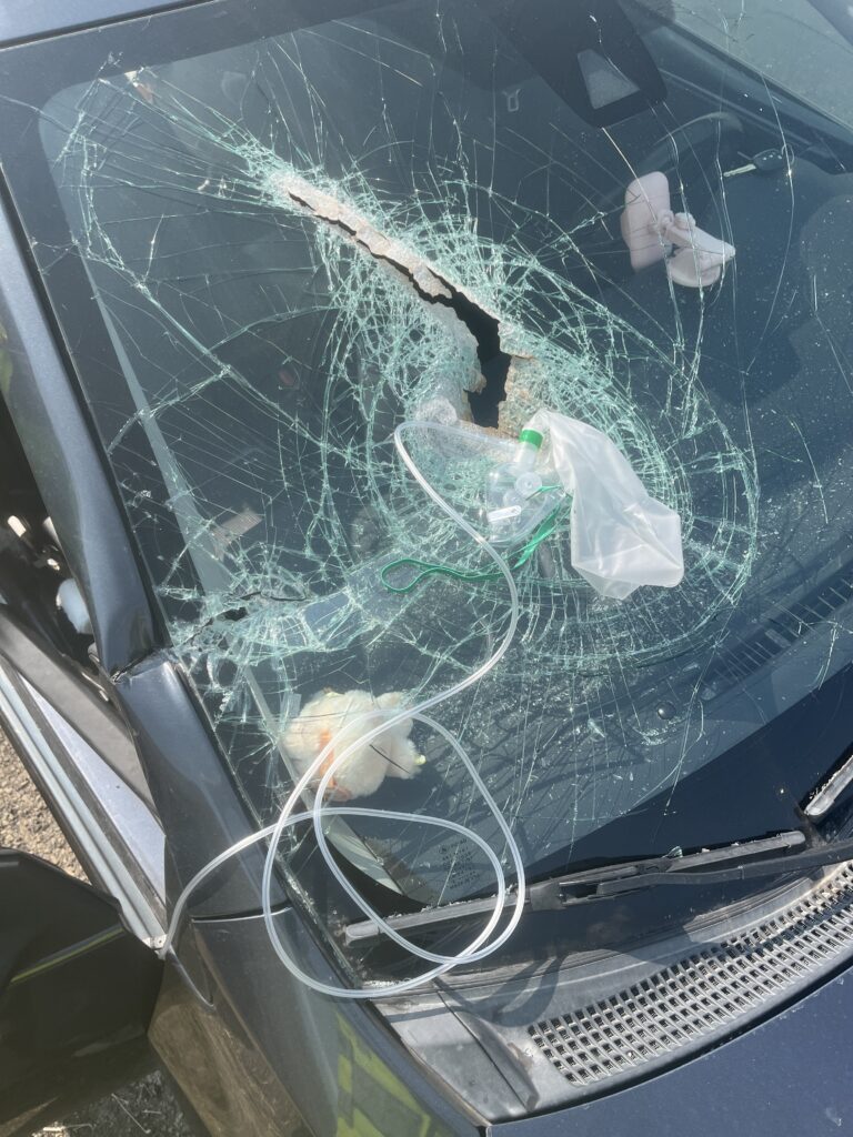 Debris hits passenger after coming through vehicles windshield.