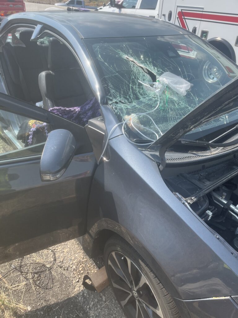 Debris hits passenger after coming through vehicles windshield.