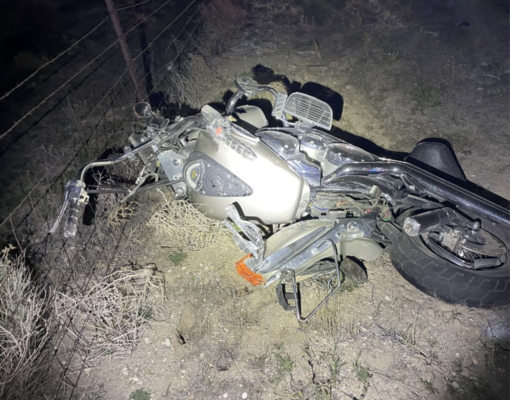Damaged motorcycle laying on its side on the dirt shoulder
