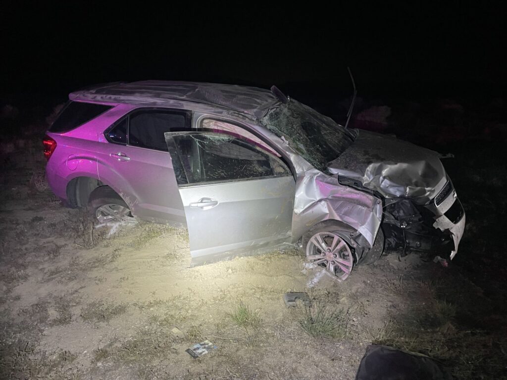 Passenger side view of an SUV with front end damage, air bags deployed, and windshield smashed. 