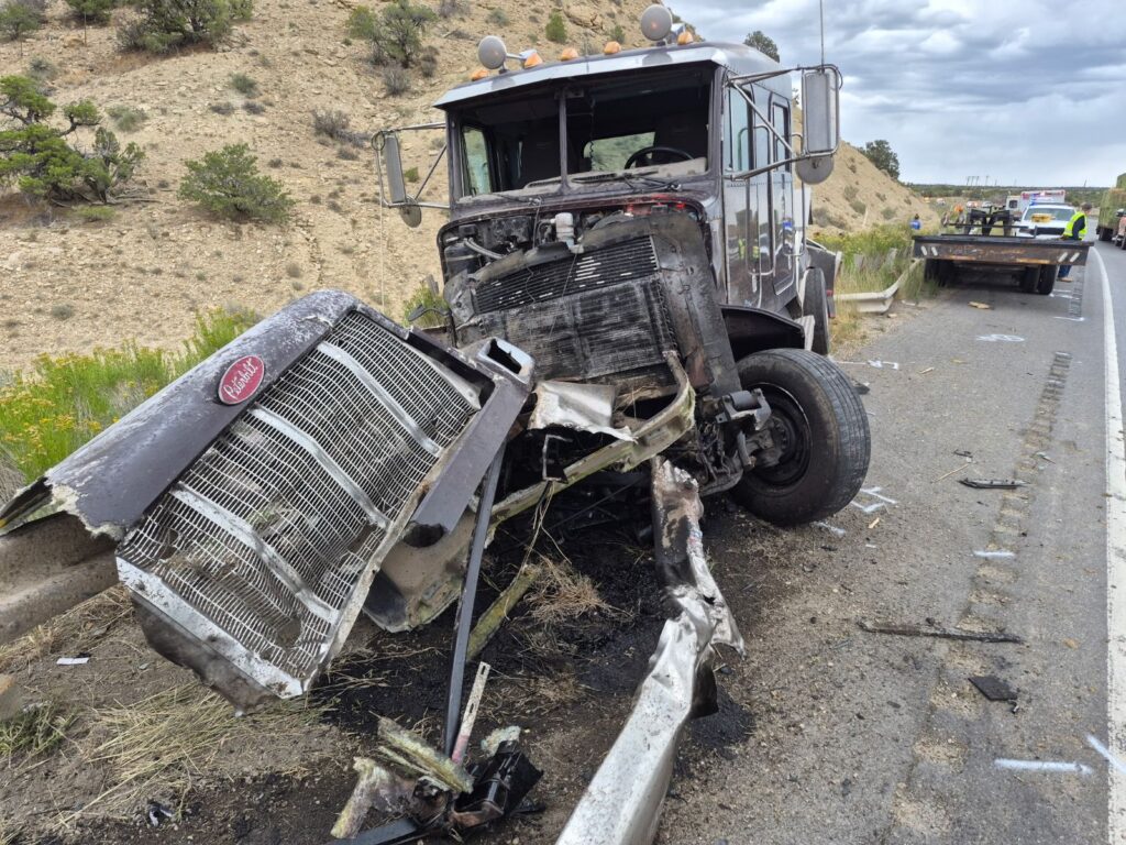 Front end of a burnt semi cab on the side of the highway.