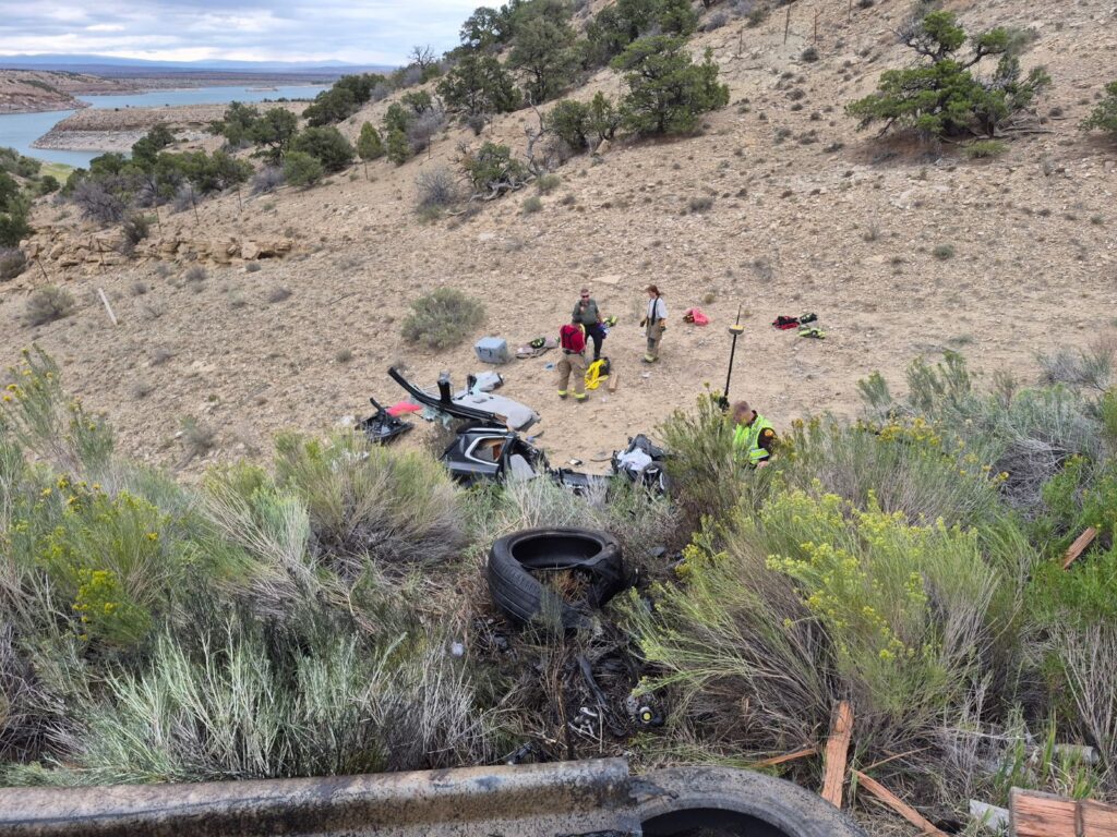 Damaged Kia down an embankment with first responders around.